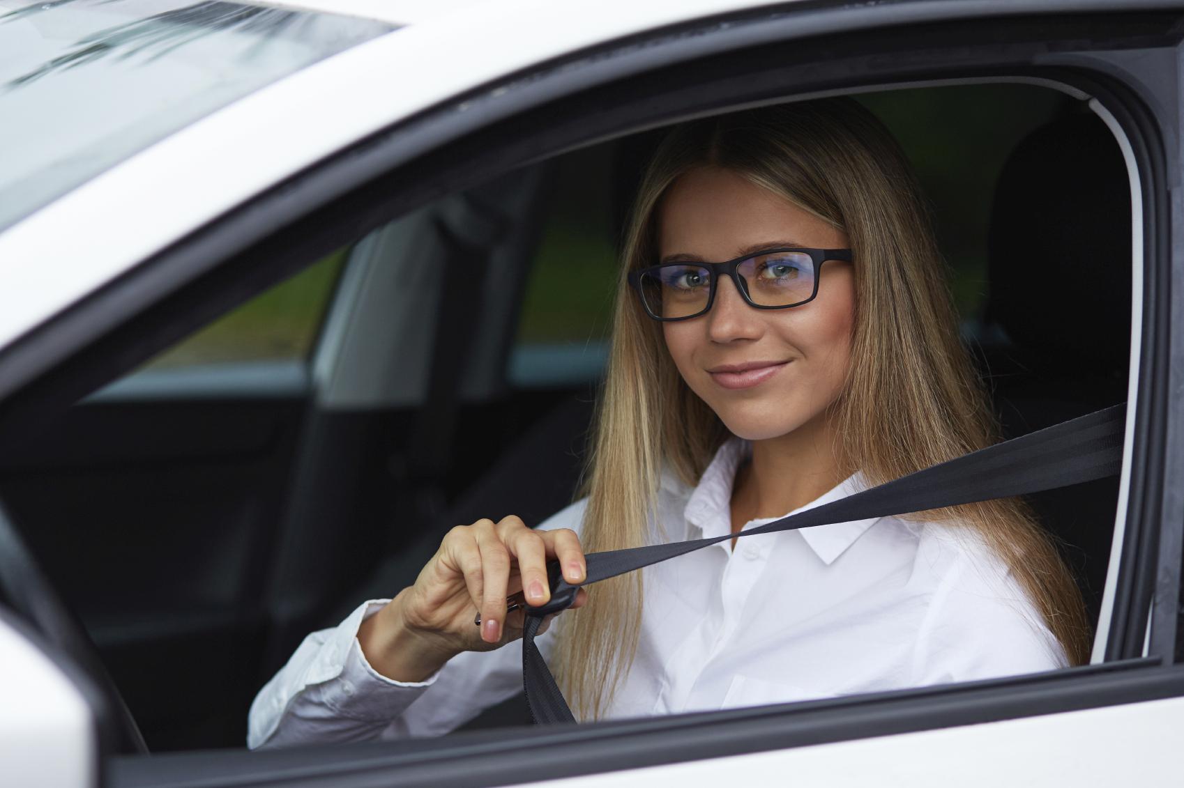 Chica con gafas poniéndose el cinturón en un coche