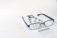 Gafas negras sobre optotipo en mesa blanca