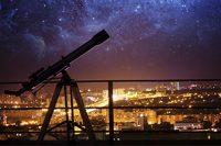 Telescopio frente a ciudad iluminada
