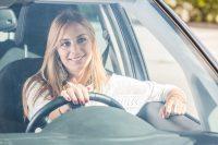 Mujer rubia sonriendo mientras conduce