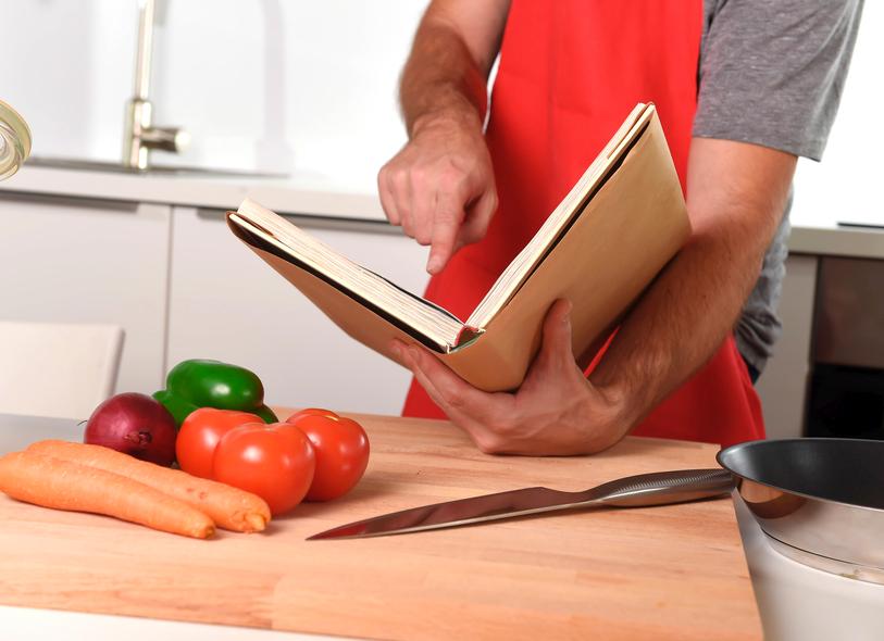 unrecognizable man at kitchen following recipe book healthy cooking