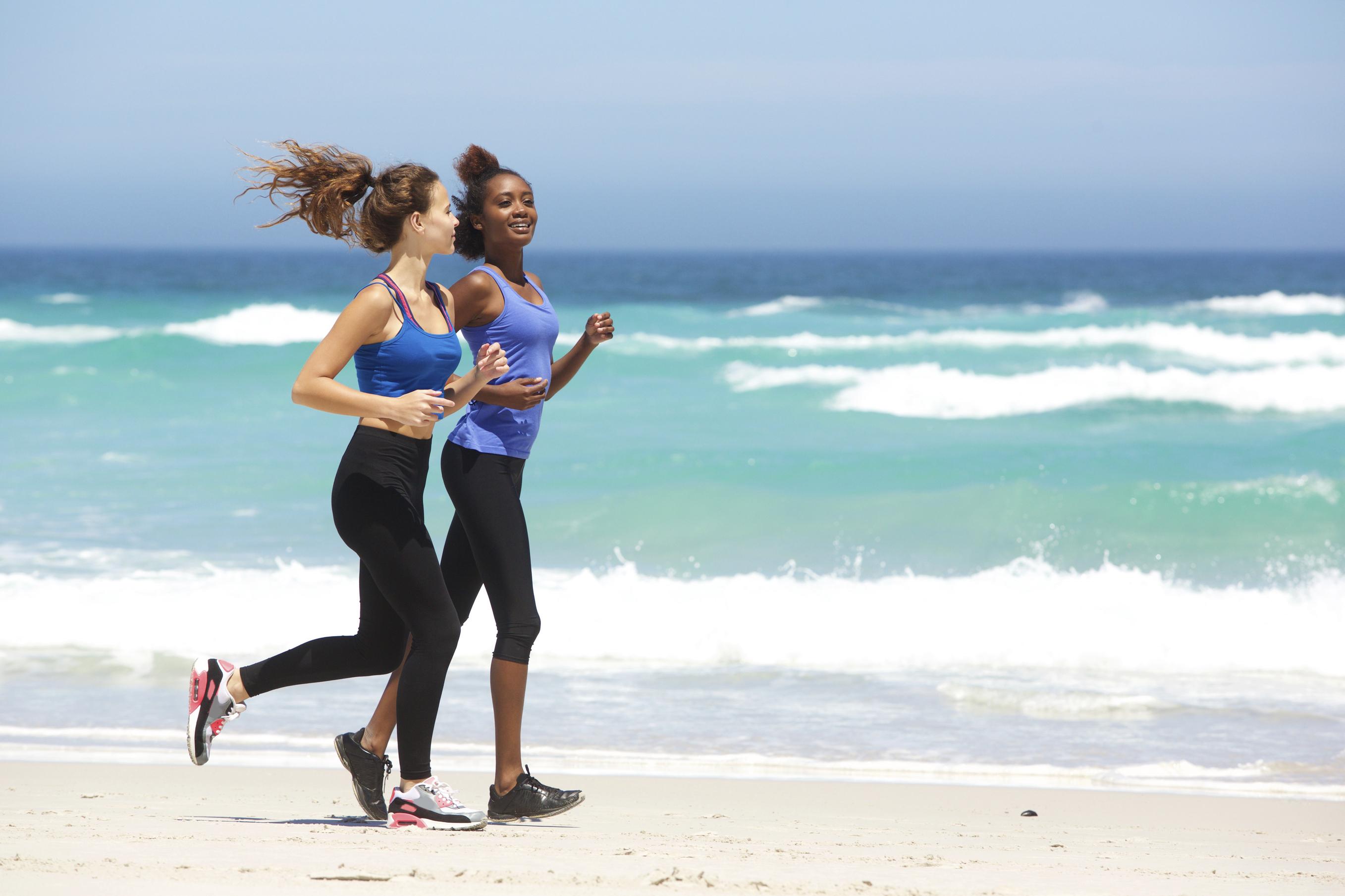 Two young women running along the beach