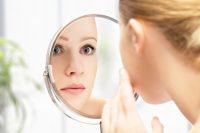 Mujer rubia mirándose la cara en un espejo