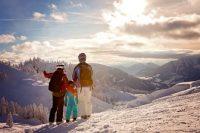 Pareja y niño en la nieve mirando montañas