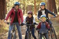 Pareja y dos niños montando en bicicleta por el bosque