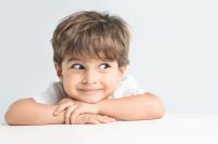 Niño con camiseta blanca se apoya en sus brazos