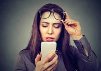 Mujer se levanta las gafas para consultar móvil