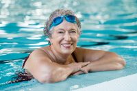 Mujer en borde de piscina con gafas de nadar