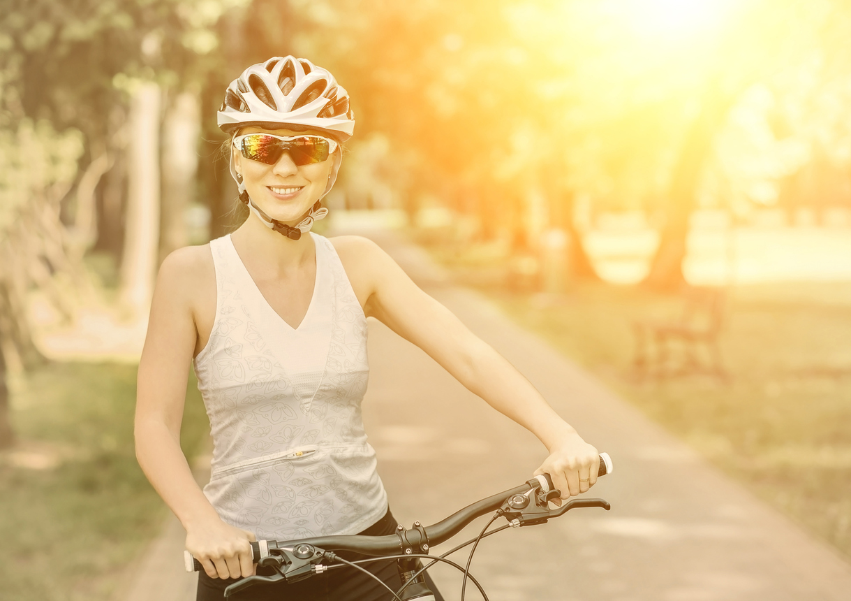 Mujer ciclista con casco y gafas al sol