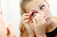 Mujer rubia quitándose una lente de contacto