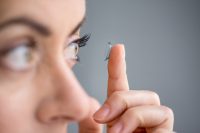 Mujer poniéndose lente de contacto con un dedo