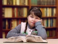 Niña con trenzas leyendo un libro