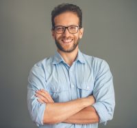 Hombre con camisa azul y gafas cruza los brazos