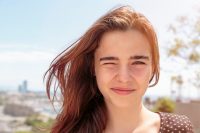 Mujer pelirroja con ojos marrones guiñando un ojo