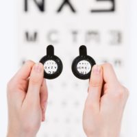 Manos enseñando lentes frente a optotipo