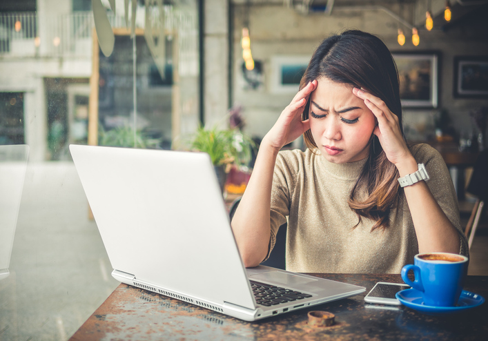 Mujer trabajando frente al ordenador con dolor de cabeza