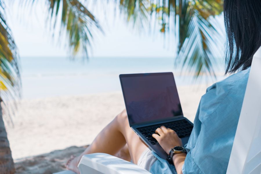 Mujer trabajando en un ordenador en la playa